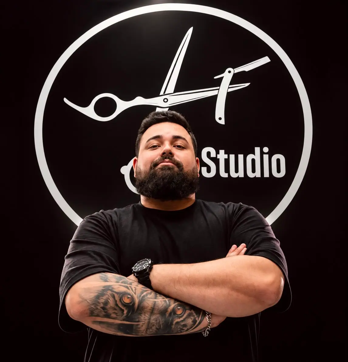 Barbeiro da LF Studio de braços cruzados em frente ao logo do estúdio